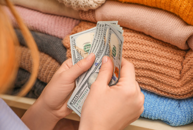 Photo of Woman hiding money between clothes in wardrobe, closeup. Financial savings