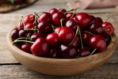 Photo of Fresh ripe cherries in bowl on wooden table, closeup