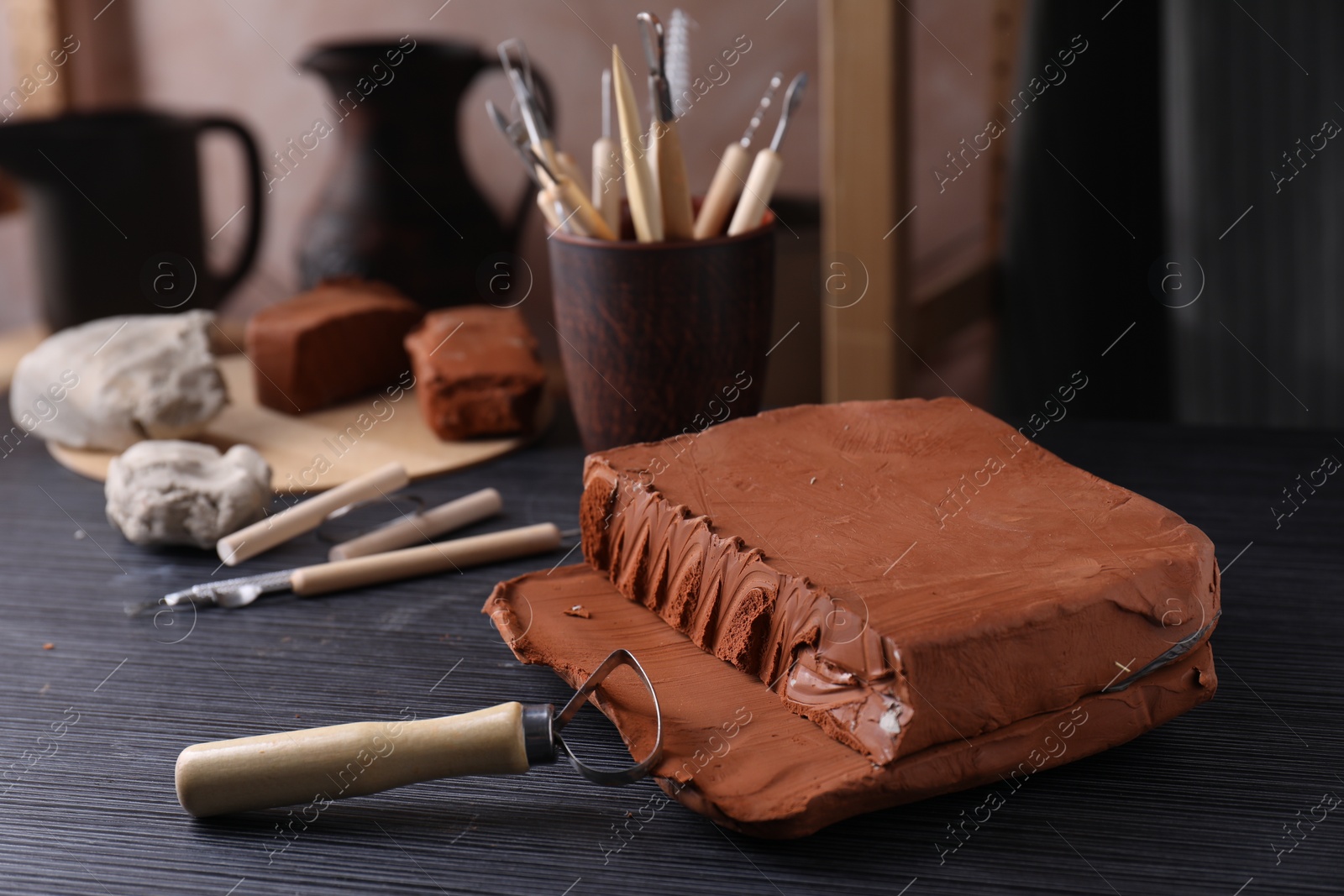 Photo of Clay and loop tool on dark gray wooden table in workshop