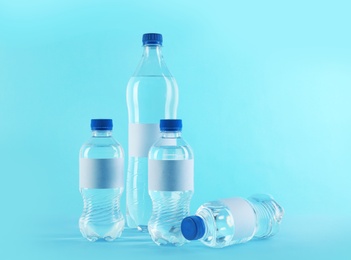 Photo of Different bottles of pure water with blank tags on color background