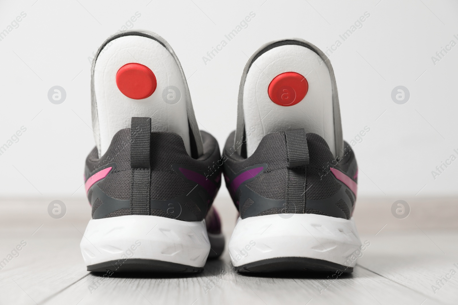 Photo of Orthopedic insoles in shoes on floor, closeup