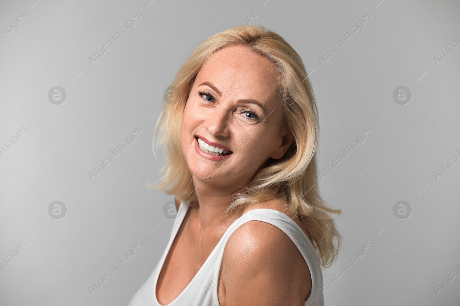 Photo of Portrait of beautiful mature woman with perfect skin on grey background