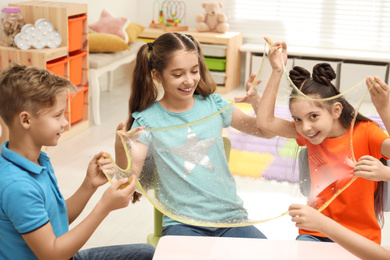 Photo of Happy children playing with slime at table indoors