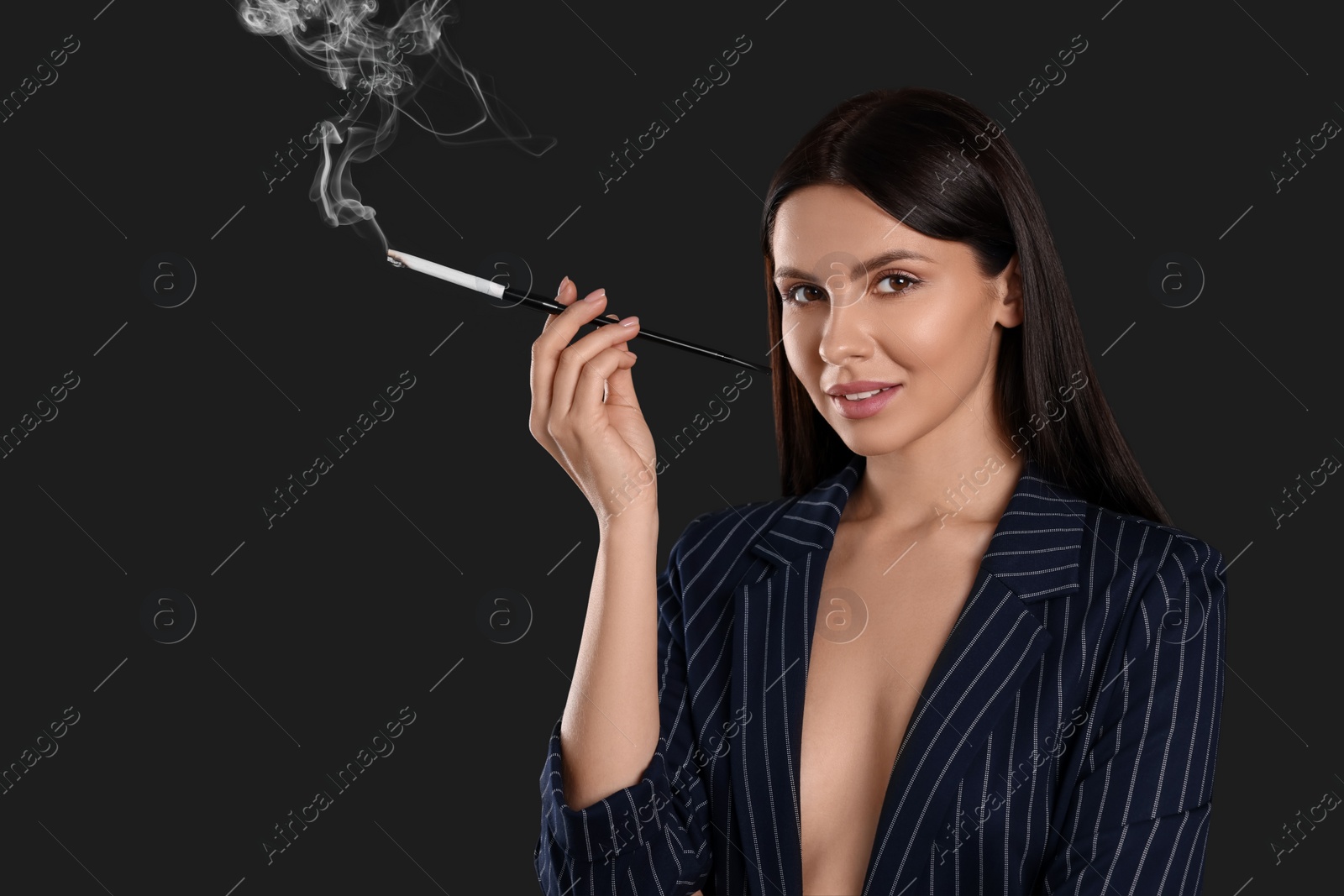 Photo of Woman using long cigarette holder for smoking on black background