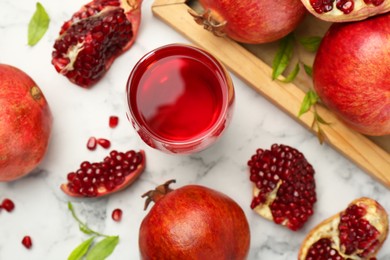 Photo of Tasty pomegranate juice in glass and fresh fruits on white marble table, flat lay
