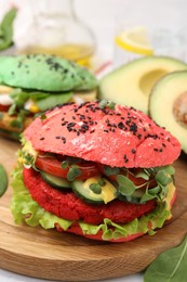 Photo of Tasty pink vegan burger with vegetables, patty and microgreens on white table, closeup