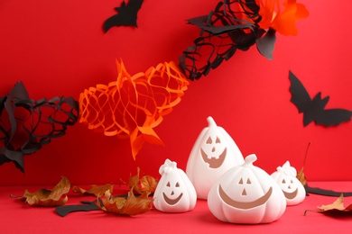 Photo of Composition with pumpkin shaped candle holders on red background. Halloween decoration