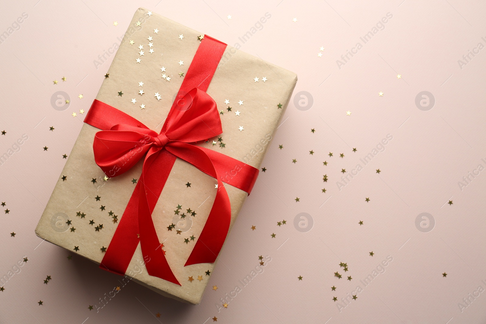 Photo of Gift box and confetti stars on light background, flat lay. Christmas celebration