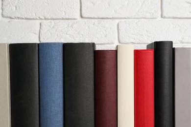 Many different hardcover books near white brick wall, space for text