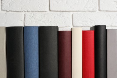 Photo of Many different hardcover books near white brick wall, space for text