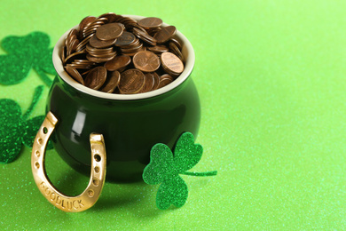 Photo of Pot of gold coins, horseshoe and clover on green background. St. Patrick's Day celebration