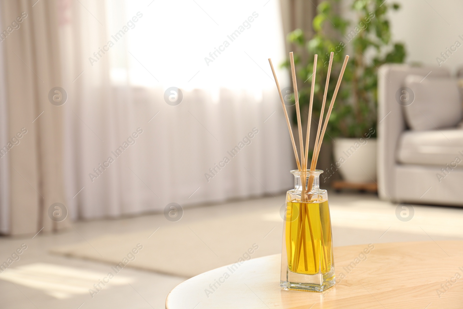 Photo of Reed air freshener with essential oil on table in room. Space for text