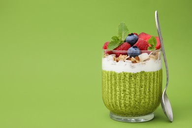 Photo of Tasty matcha chia pudding with oatmeal and berries on green background, space for text. Healthy breakfast