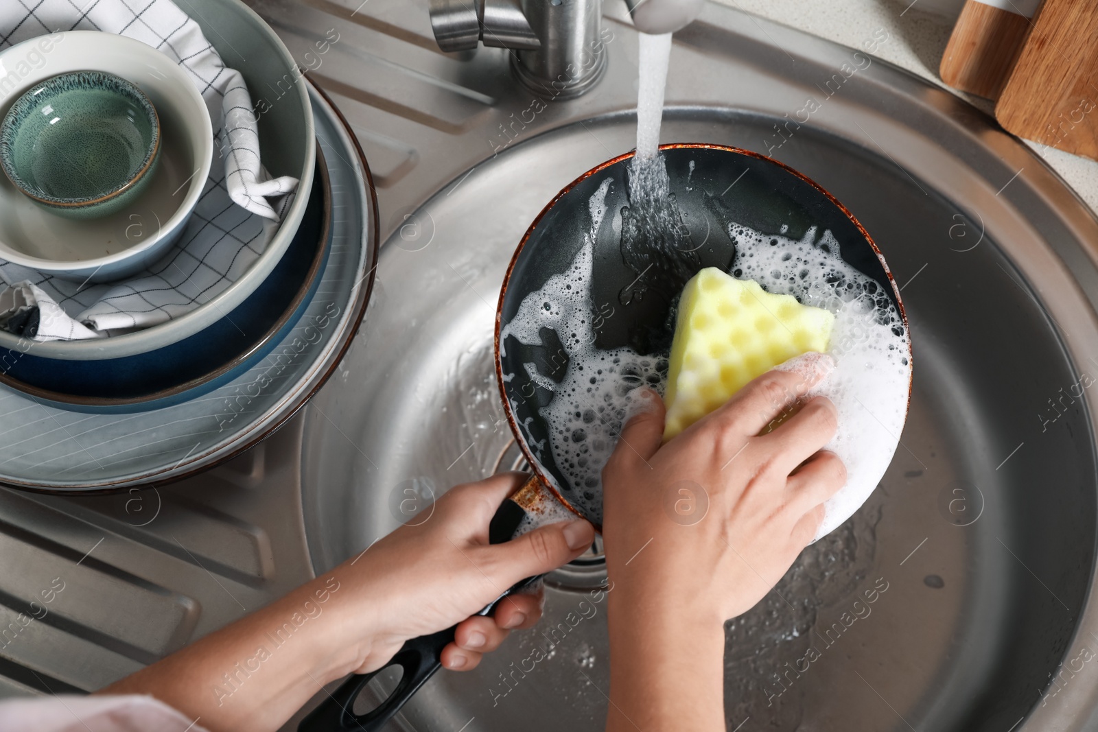 Photo of Woman washing dirty frying pan in sink, above view