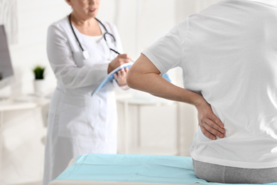 Photo of Female orthopedist examining patient with injured back in clinic, closeup