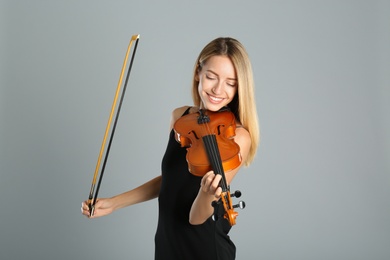 Photo of Beautiful woman with violin on grey background