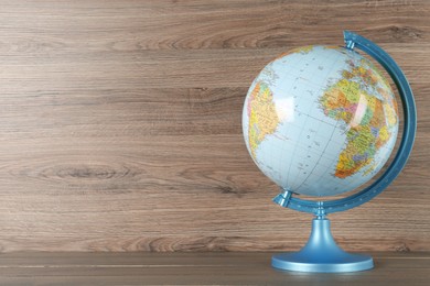 Photo of Plastic model globe of Earth on wooden table, space for text. Geography lesson