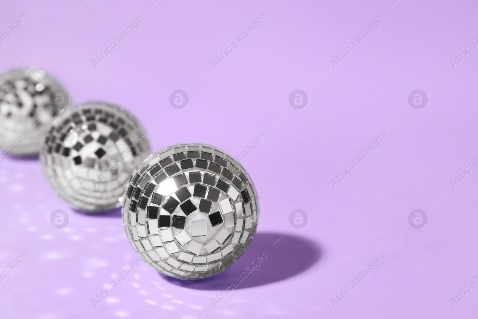 Photo of Shiny disco balls on lilac background. Space for text