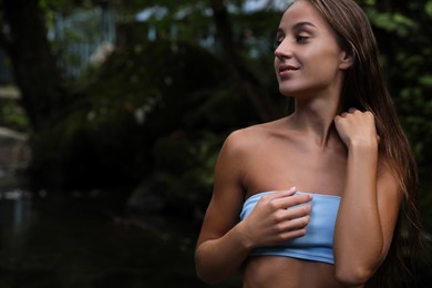 Photo of Beautiful young woman in light blue bikini near mountain river outdoors. Space for text