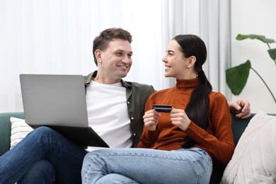 Photo of Happy couple with laptop and credit card shopping online together at home