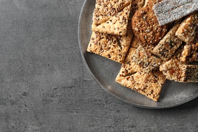 Photo of Plate with cookies and cereal bars on grey background, top view. Whole grain snack