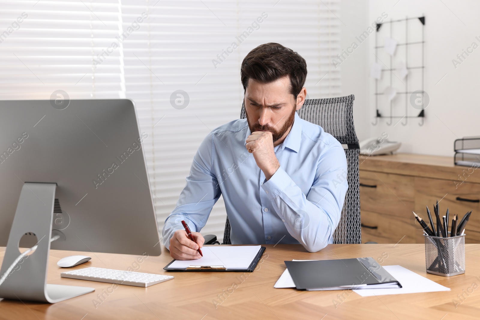 Photo of Sick man coughing at workplace in office. Cold symptoms