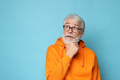 Photo of Senior man with mustache on light blue background, space for text