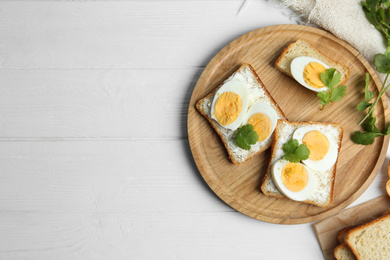 Photo of Tasty sandwiches with boiled eggs served on white wooden table, flat lay. Space for text