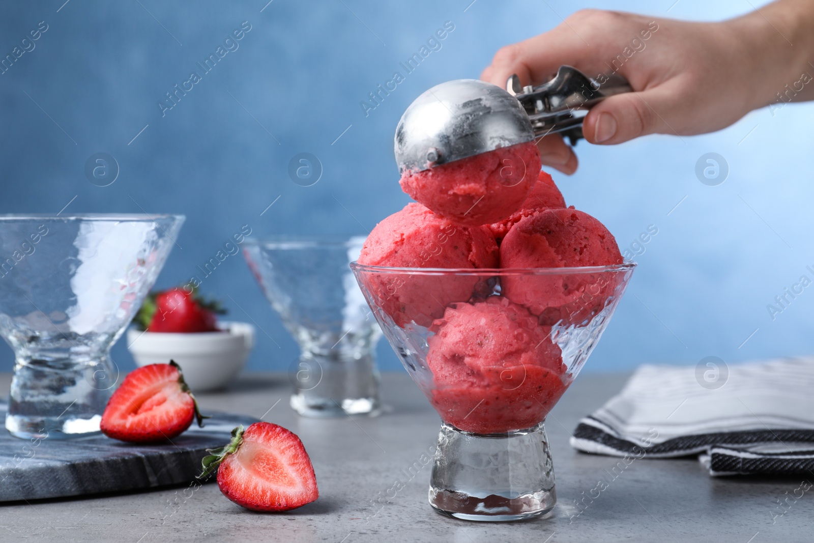 Photo of Woman putting strawberry ice cream into dessert bowl at table, closeup