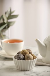 Photo of Different delicious vegan candy balls on white marble table indoors