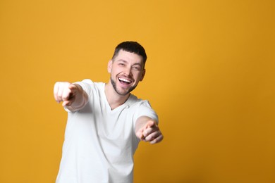Photo of Handsome man laughing on yellow background, space for text. Funny joke