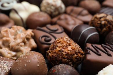 Photo of Different delicious chocolate candies as background, closeup