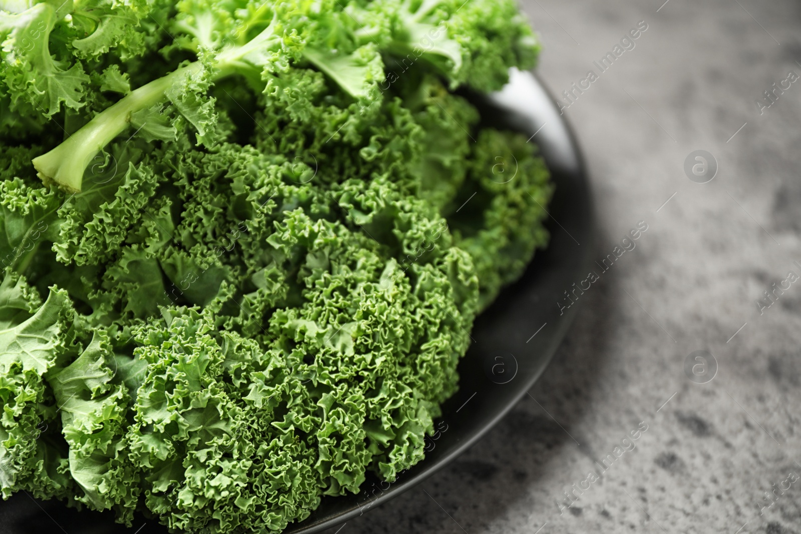 Photo of Fresh kale leaves on grey table, closeup