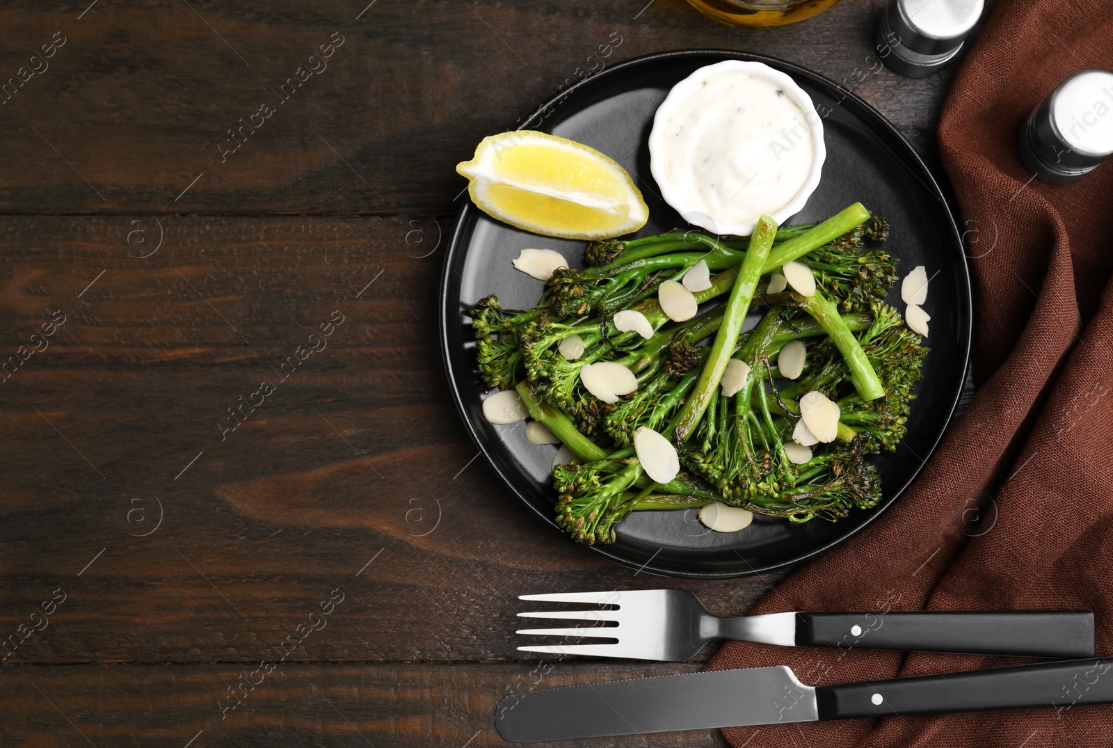 Photo of Tasty cooked broccolini served on wooden table, flat lay. Space for text