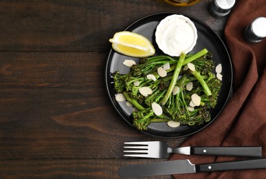 Tasty cooked broccolini served on wooden table, flat lay. Space for text