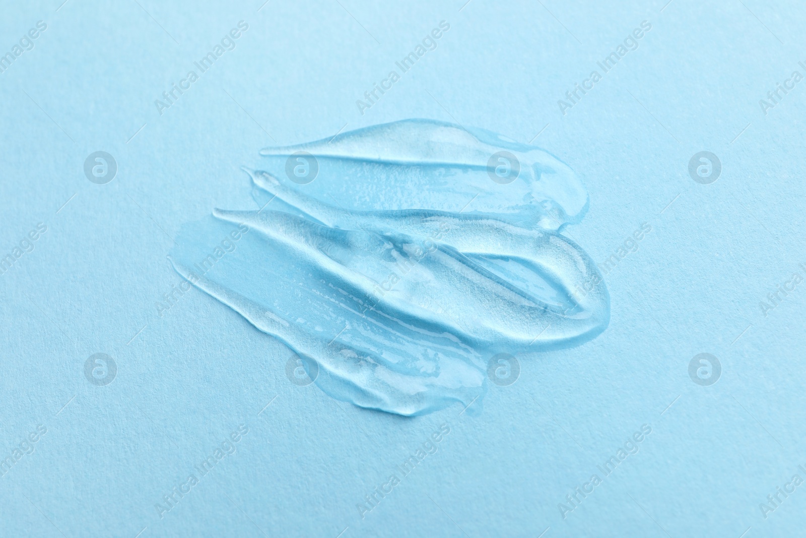 Photo of Swatches of cosmetic gel on light blue background, top view