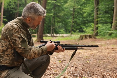 Man with hunting rifle wearing camouflage in forest