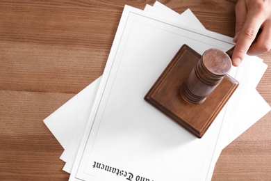 Male notary with gavel and documents at wooden table, top view