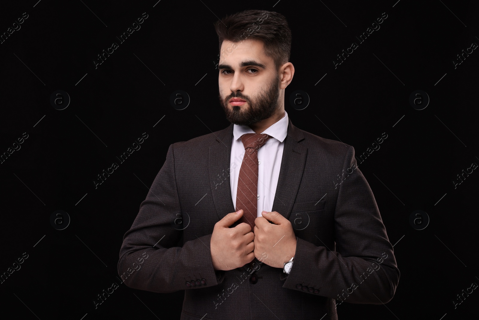 Photo of Handsome businessman in suit and necktie on black background