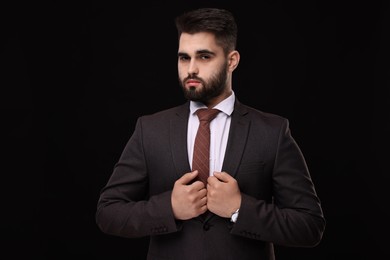 Photo of Handsome businessman in suit and necktie on black background