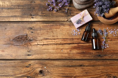 Cosmetic products and lavender flowers on wooden table, flat lay. Space for text