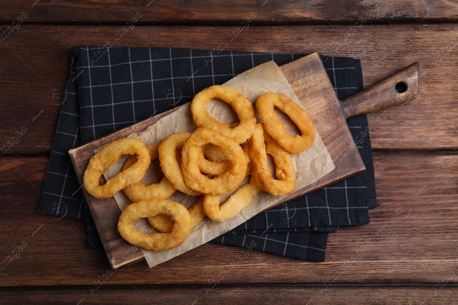 Photo of Fried onion rings served on wooden table, top view