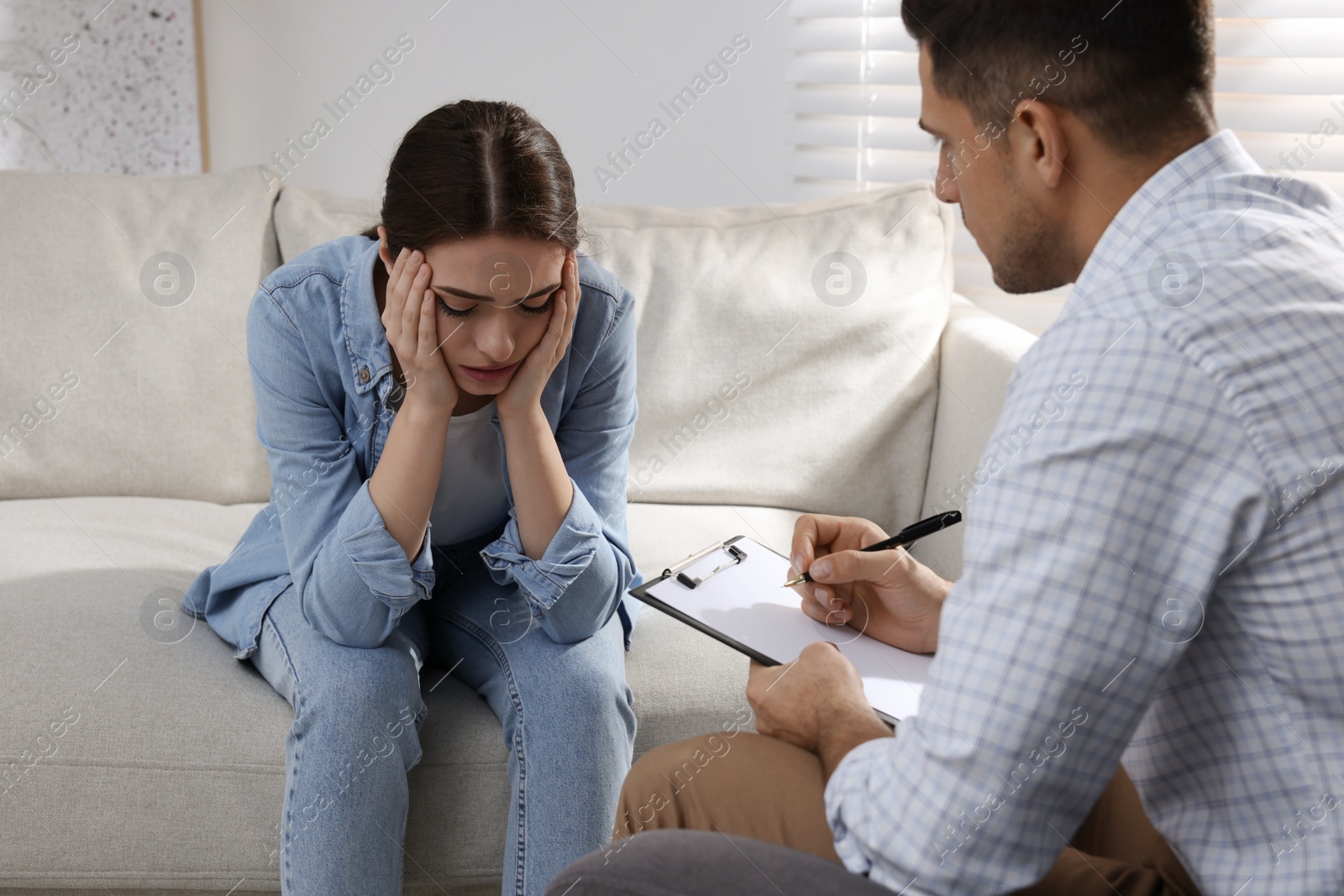 Photo of Unhappy young woman having session with her therapist indoors