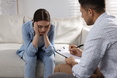 Photo of Unhappy young woman having session with her therapist indoors