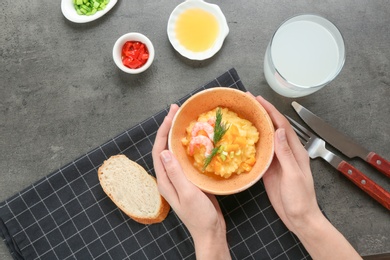 Woman with bowl of fresh tasty shrimp and grits on grey background