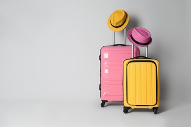 Photo of Travel suitcases with hats on light grey background, space for text. Summer vacation