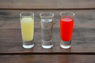 Shots with lime juice, tequila and sangria as colors of mexican flag on wooden table. Traditional serving