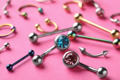 Photo of Stylish piercing jewelry on pink background, closeup