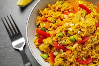 Photo of Delicious rice pilaf with vegetables on grey table, closeup