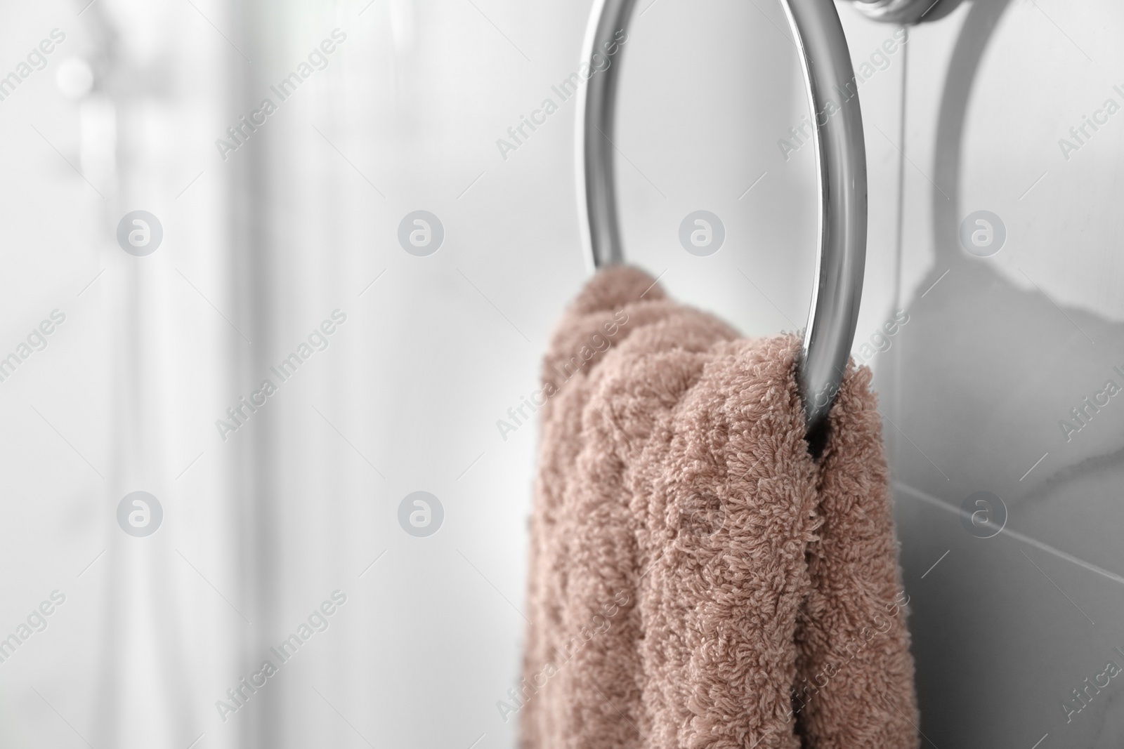 Photo of Holder with clean towel on light wall in bathroom, closeup